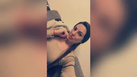 Young woman in a casual beige sweater relaxing indoors with a peaceful expression.