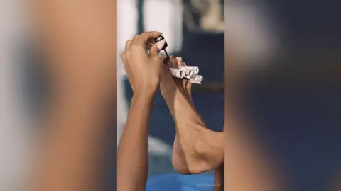 MarisaGrace holds a rolled-up bill against the sole of her bare foot, showing off her toes and feet.