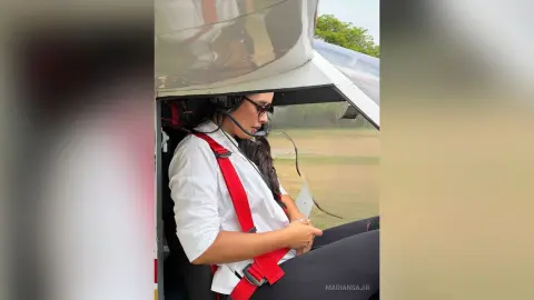 MarianSajir sits in a helicopter wearing a white shirt and black leggings, looking out the side window.