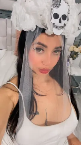 Woman in white dress and skull floral veil posing with a dreamy, ethereal mood.