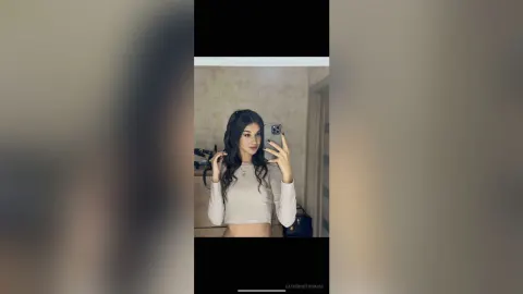 CatherineThomase — CatherineThomase takes a mirror selfie wearing a white long-sleeve crop top.
