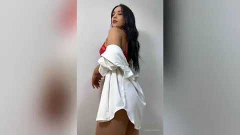 Elegant woman in a white oversized shirt and red lace lingerie posing against a minimalist white background.