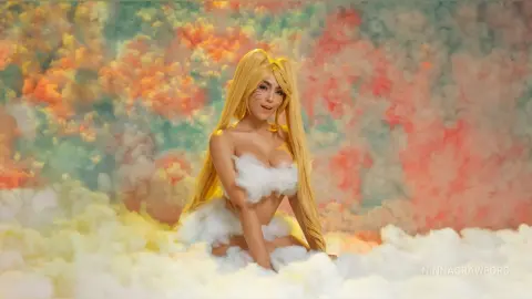 Blonde woman in a white fluffy cloud outfit sitting amidst colorful pastel dreamlike clouds.