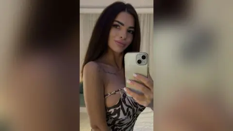Young woman in a zebra print top taking a selfie in a bright indoor setting.