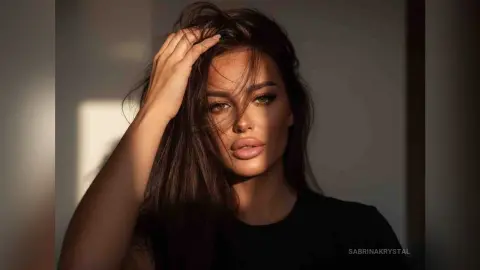 Brunette woman in a black top posing in warm sunlight for a moody, cinematic portrait.