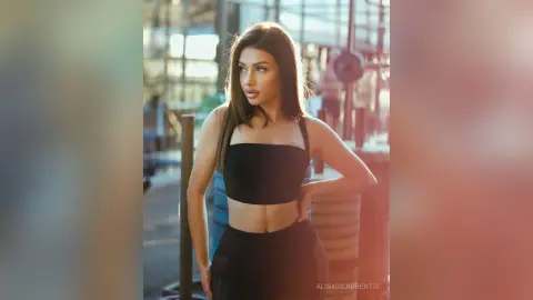 Athletic woman in black gym wear posing in a sunlit fitness studio during a golden hour workout.