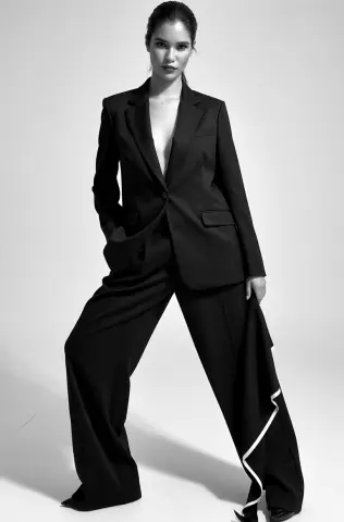 Elegant woman in a black tailored power suit posing in a minimalist studio setting with a sophisticated mood.