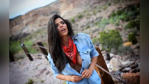 DrellaWolf — Beautiful woman in denim shirt and red bandana posing in a sunny desert landscape.