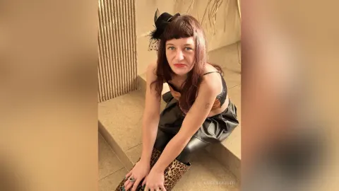SabrinaBauer — SabrinaBauer sits on stairs wearing a black lace bra and a black leather skirt.
