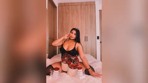 Young woman in black lace lingerie and floral corset sitting on a bed in a modern bedroom.
