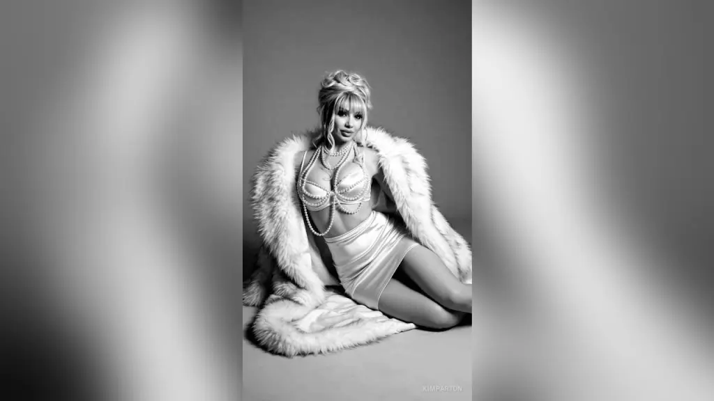 Blonde woman in black angel wings and leather cosplay outfit posing by a white vintage car in the snow.