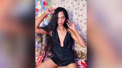 Young woman in a sleek black plunging bodysuit posing confidently against a patterned backdrop.