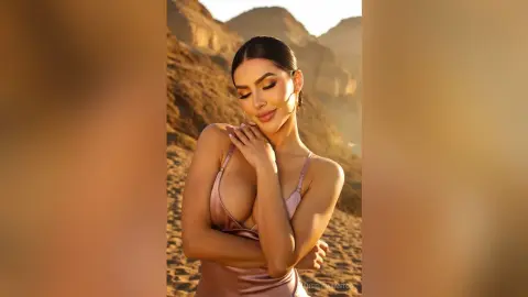 Elegant woman in a satin slip dress posing during a golden hour desert sunset photoshoot.