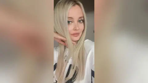 DianeDavies poses with her long blonde hair framing her face while wearing a white t-shirt.