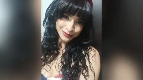 BrendaaLocke — BrendaaLocke smiles at the camera with long wavy black hair and dark red lipstick.