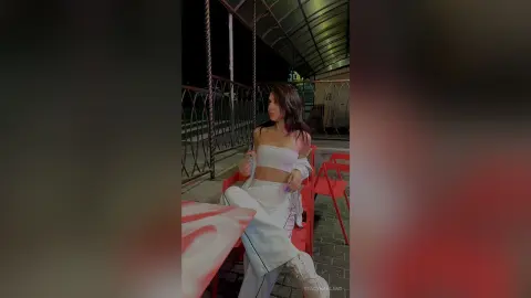 StacyHarland — StacyHarland poses in a white tube top and matching white pants while sitting outdoors at night.