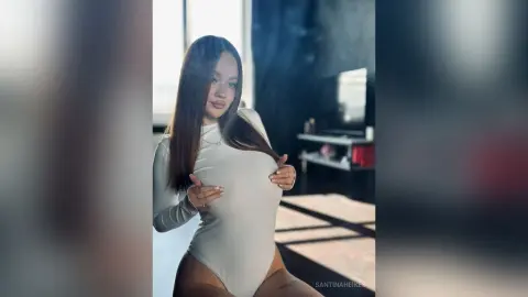 SantinaHeikes poses in a tight white bodysuit, pulling the fabric down to show her breasts.