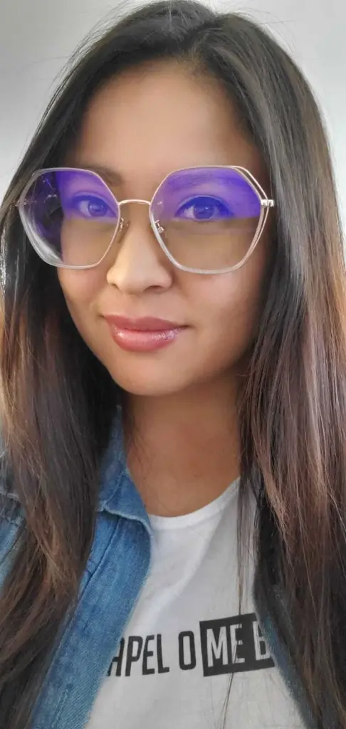 Hanna_backerr — Smiling woman with long dark hair wearing glasses, a denim jacket, and a white graphic t-shirt.