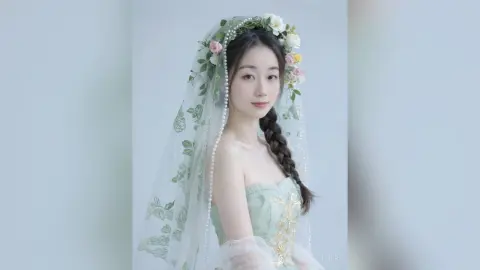 Elegant bride in a mint green lace gown and floral veil posing with a dreamy, romantic expression.