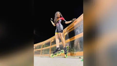 Athletic woman in black bodysuit rollerblading on a city bridge at night with a confident mood.
