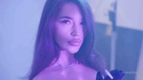 Young woman with long hair wearing a silver necklace in dreamy purple neon lighting.