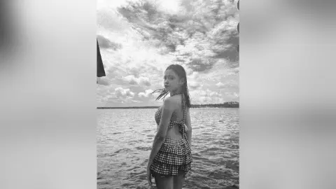 NancyLoppez stands in the ocean wearing a checkered bikini top and matching skirt, looking back over her shoulder.