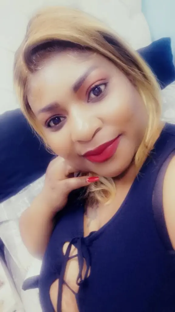EbonyhotAss40 poses with a smile, showing her long blonde hair and light pink top against a plain background.