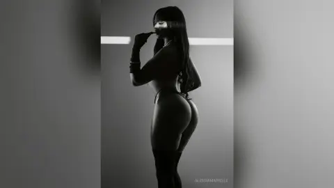 Silhouette of a woman in black lingerie and gloves posing against a minimalist studio background.