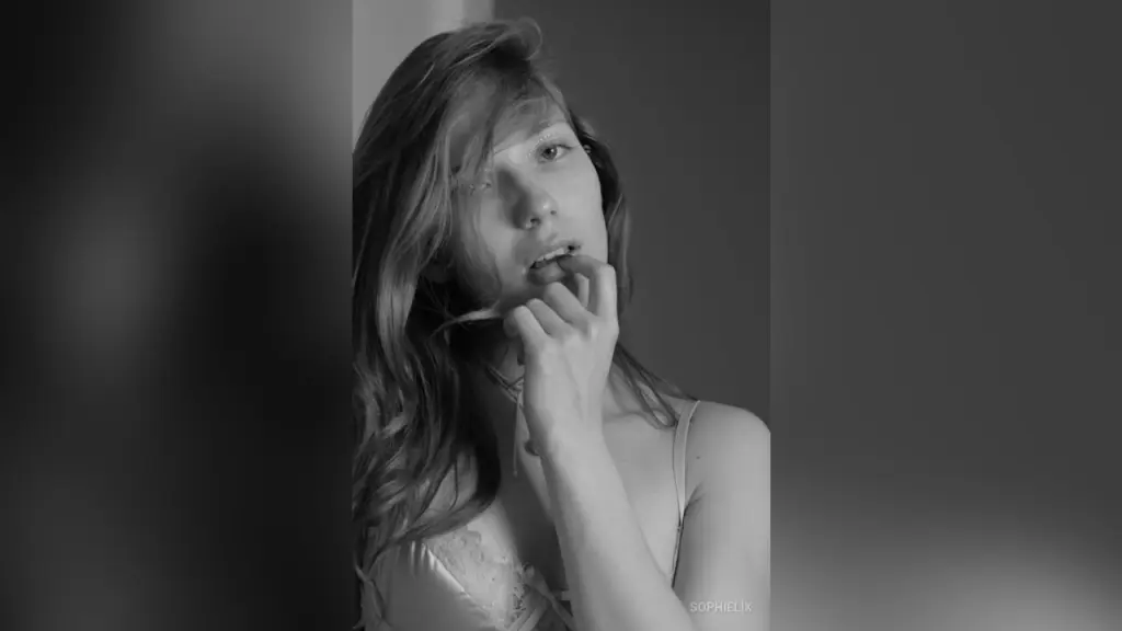 SophieLix poses with her fingers near her mouth in a black and white close-up shot.