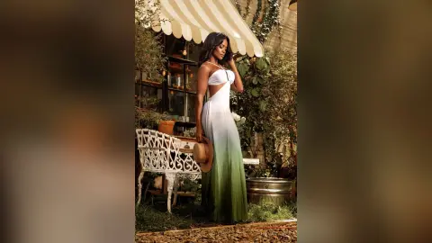 Elegant woman in a white and green ombre maxi dress posing in a lush, sunlit garden setting.