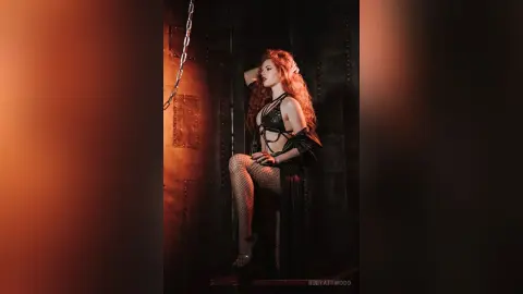 RubyAttwood poses in black strappy lingerie and fishnet stockings against a dark, industrial metal wall.