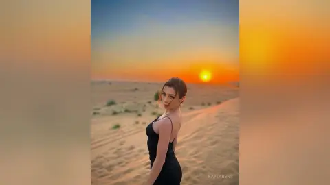 Elegant woman in a black dress posing against a golden desert sunset sky.