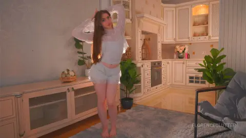Young woman in white lace loungewear relaxing in a bright, modern aesthetic kitchen setting.