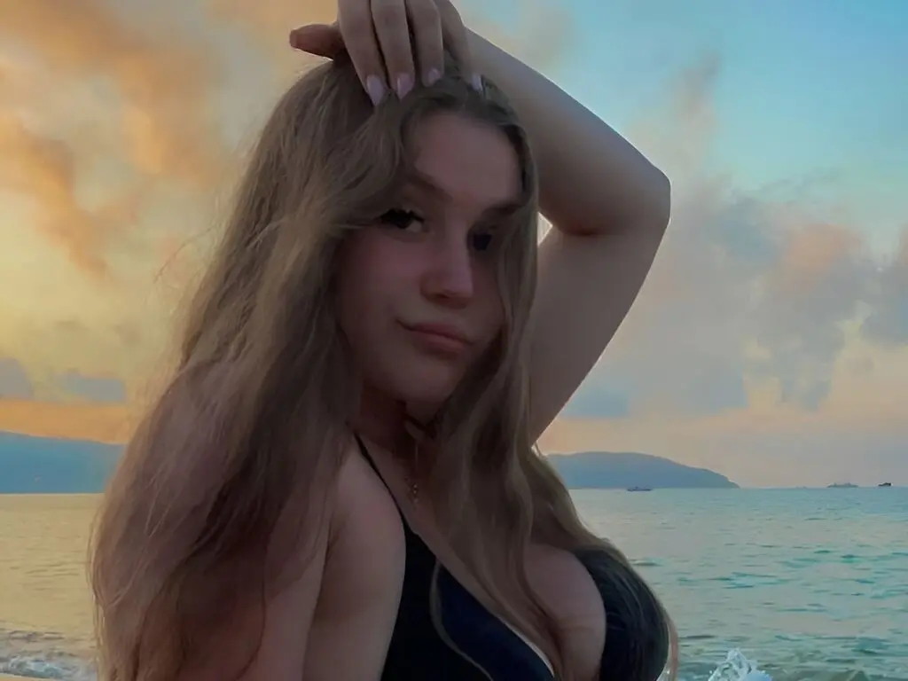 Young woman with long blonde hair in a black bikini enjoying a serene sunset at the beach.
