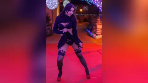 Glamorous woman in black lingerie and stockings posing under festive holiday lights at night.
