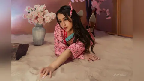 Young woman in pink patterned loungewear relaxing on a sandy beach with cherry blossoms in a dreamy mood.