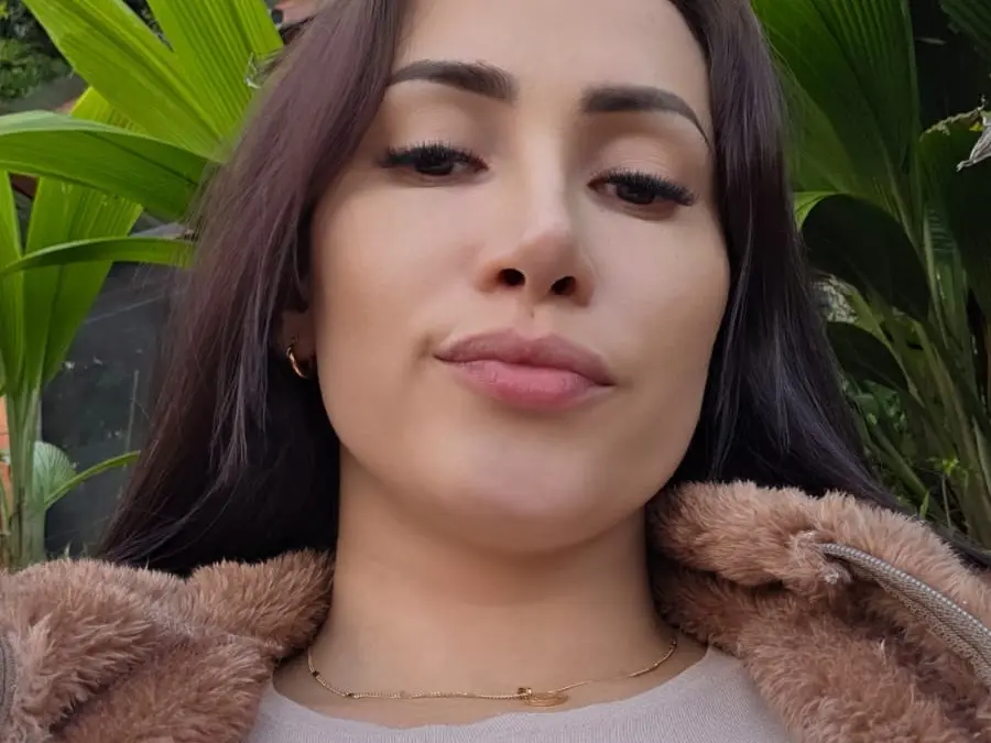 AmeliaBosch poses for a close-up selfie with long dark hair and pink lipstick.