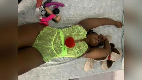 Curvy woman in lime green lace lingerie relaxing on a bed with a playful mood.