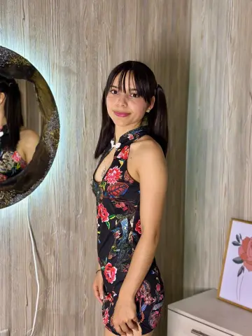 Young woman in a floral print halter dress standing in a modern room with wood paneling.