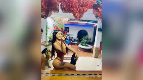 SalomeTayson wearing red devil horns and a red bikini top, posing in a mirror selfie.