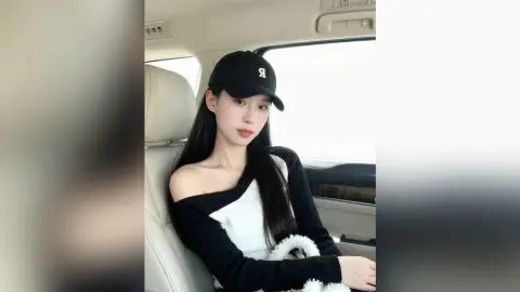 ZhiYue wears a black baseball cap and a black and white long-sleeved top while sitting in a car seat.