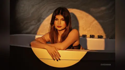 Elegant woman in a black outfit relaxing in a luxury bathtub under warm, moody golden lighting.