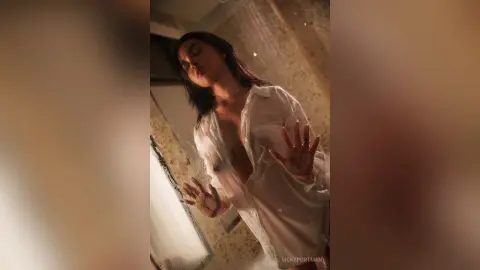 VickyPortman poses in a white open shirt, letting it hang off her shoulders while she looks down with a soft expression.