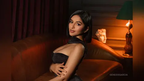 Elegant woman in a black sequin dress sitting on a velvet sofa in a moody, dimly lit vintage room.