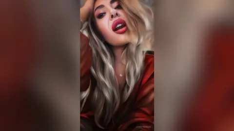 Glamorous woman with blonde hair and red lipstick wearing a silk red robe in a moody indoor setting.