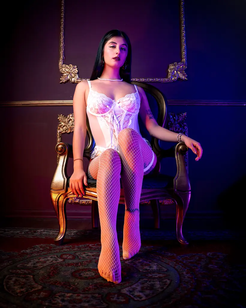 Glamorous woman with wet hair and bold makeup posing in a dark, shimmering glitter setting.