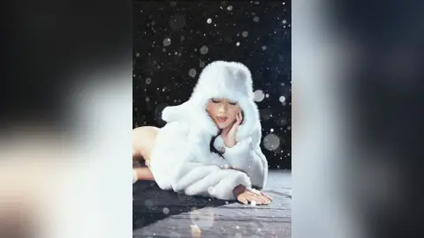 Glamorous woman in a white faux fur coat posing against a dreamy snowy backdrop.