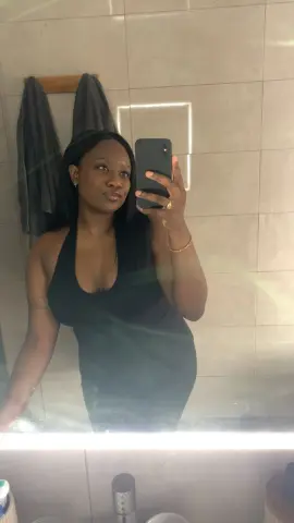 GabriellaGoldx poses for a mirror selfie wearing a black tank top with long dark hair.