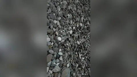 Close-up view of smooth grey and white river stones piled in a natural textured rock formation.
