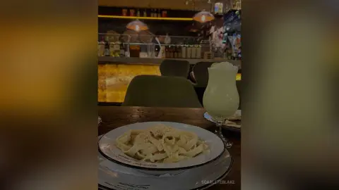 Creamy fettuccine alfredo pasta served on a white plate in a cozy, dimly lit Italian restaurant setting.